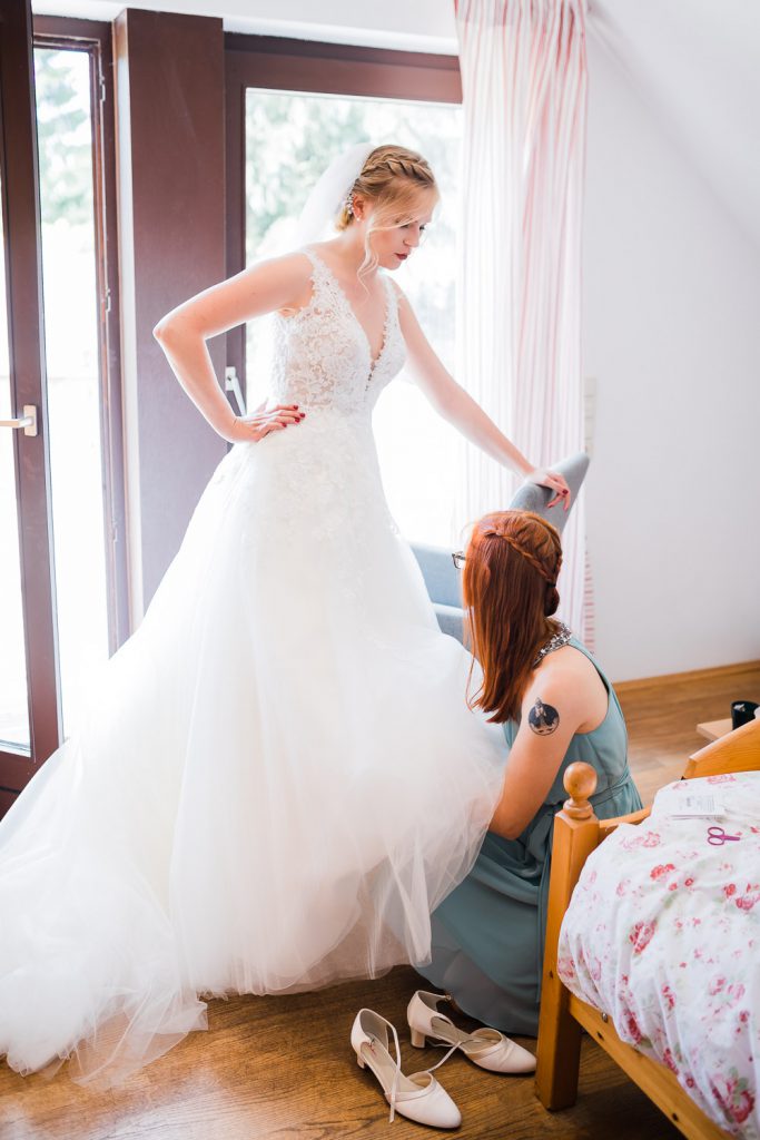 Trauzeugin zieht Braut die Schuhe an