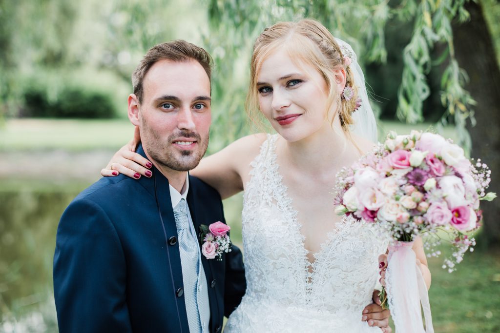 Braut sitzt bei Bräutigam auf dem Schoß