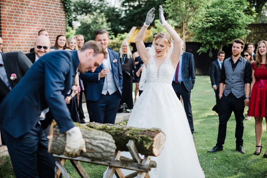 Braut und Bräutigam haben Baumstamm durchgesägt