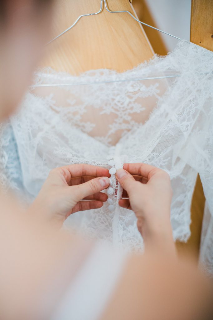 Braut öffnet Knöpfe ihres Brautkleides
