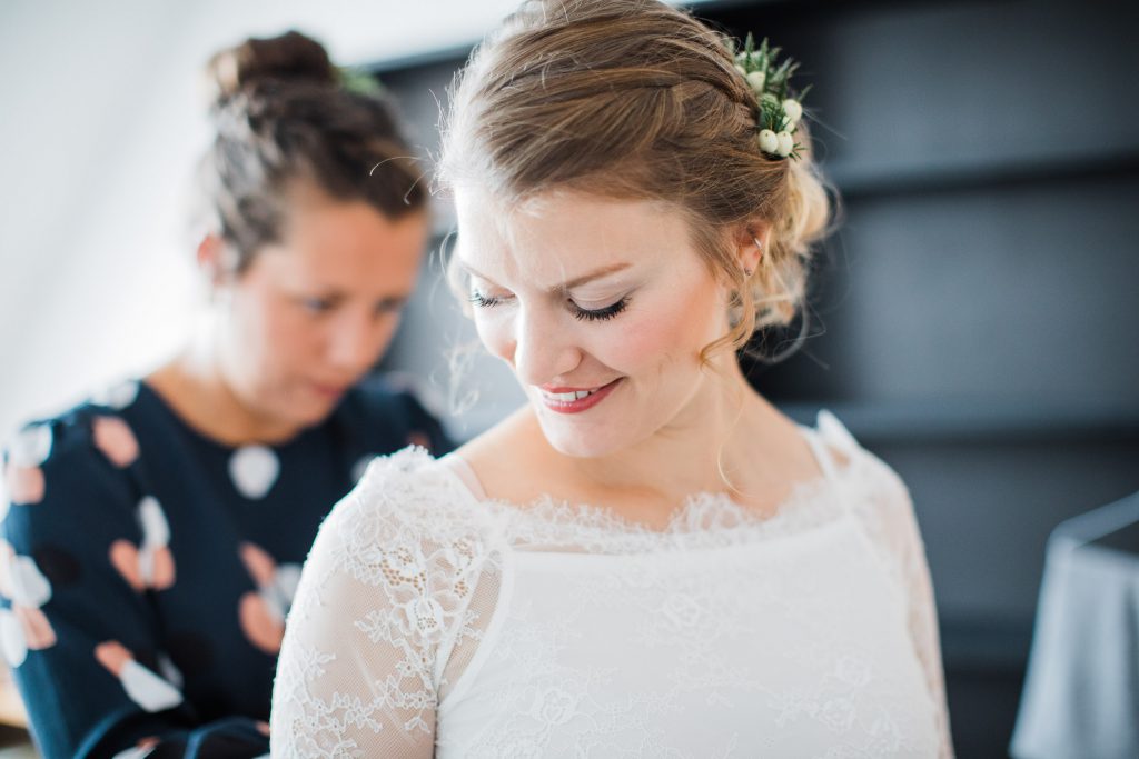 Trauzeugin schließt Braut das Brautkleid