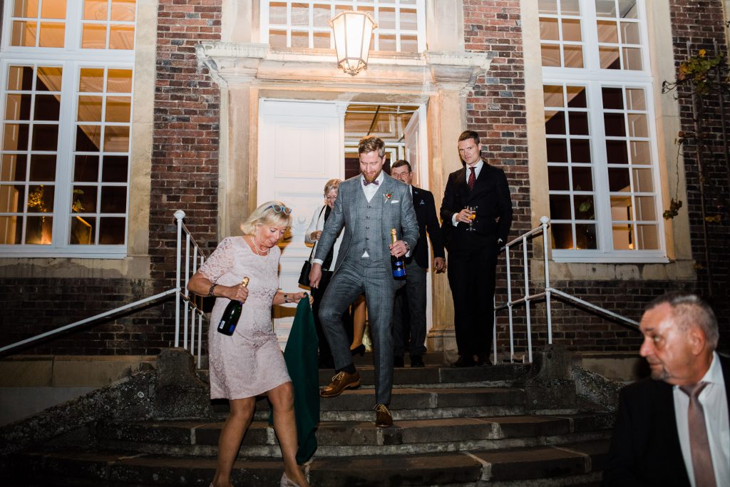 Bräutigam mit Gästen vor dem Schloss Wilkinghege