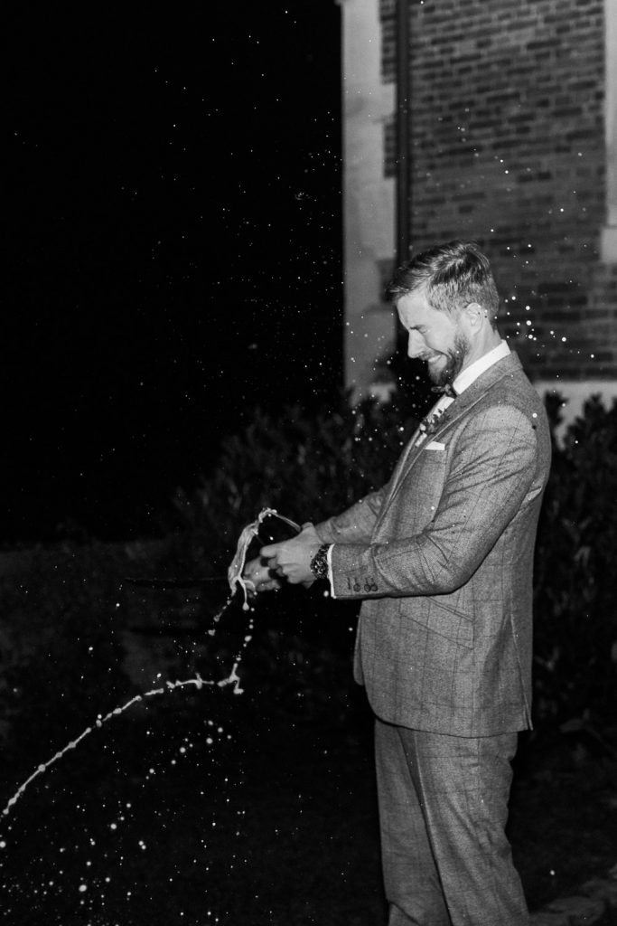 Bräutigam öffnet Flasche mit Säbel